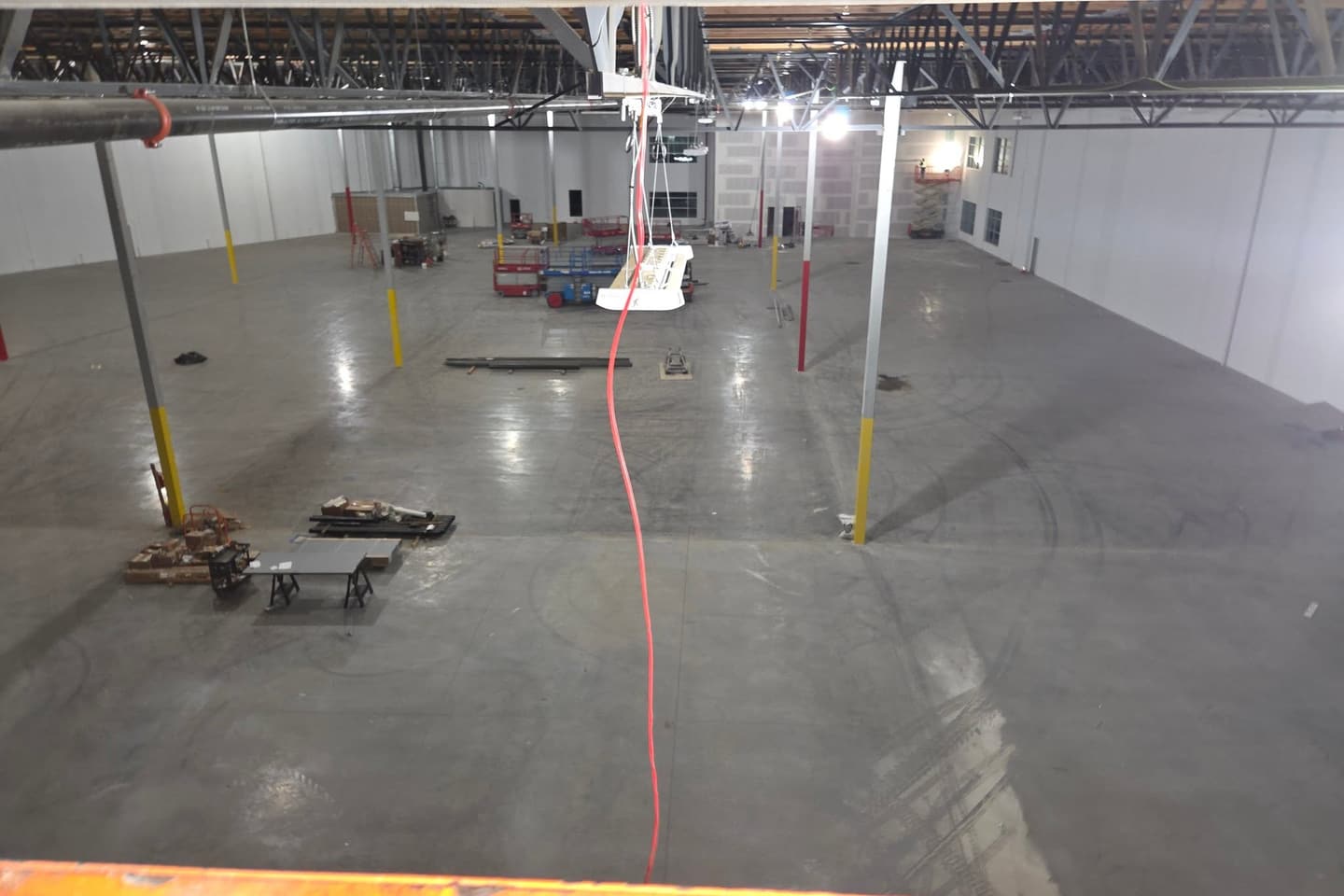 Interior of a large commercial building at construction stage, with structural columns, exposed steel framing and lifts on the slab