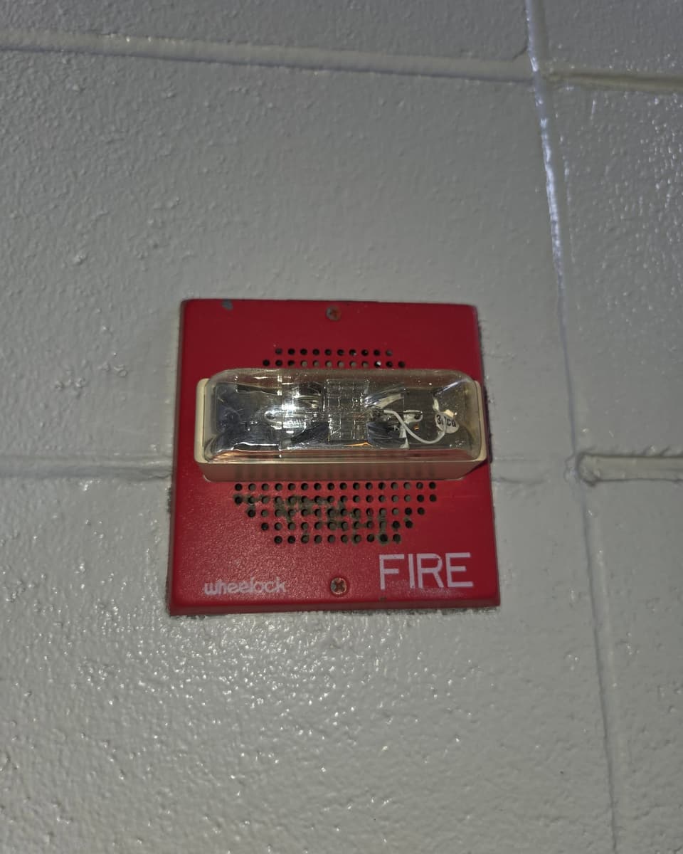 Red horn strobe labeled FIRE mounted on a painted block wall